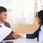 Two women shaking hands and smiling.