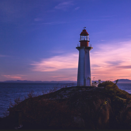 Lighthouse in the distance with a sunset.