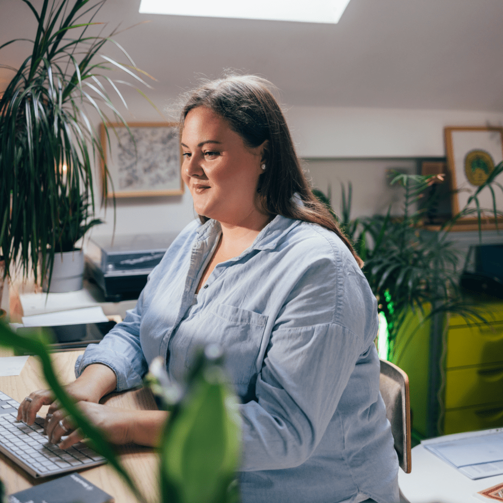 A woman smiling while typing on a laptop.